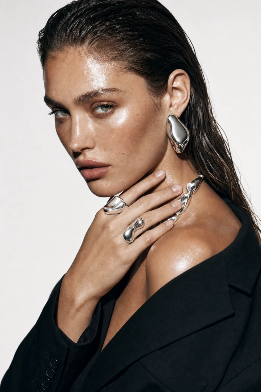 Editorial portrait with fluid silver earrings, rings and necklace